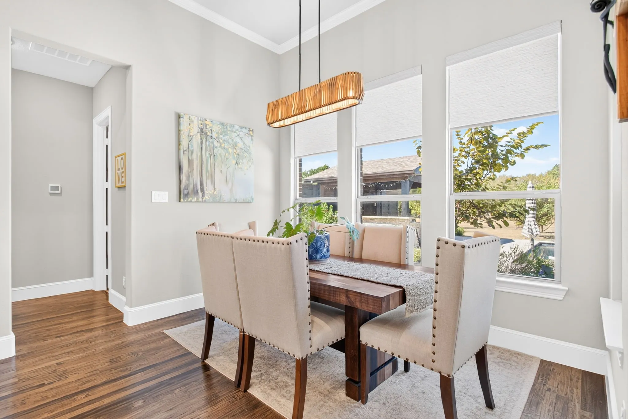 Spacious room featuring wood-finish flooring, two large windows with blinds, and a built-in linear chandelier