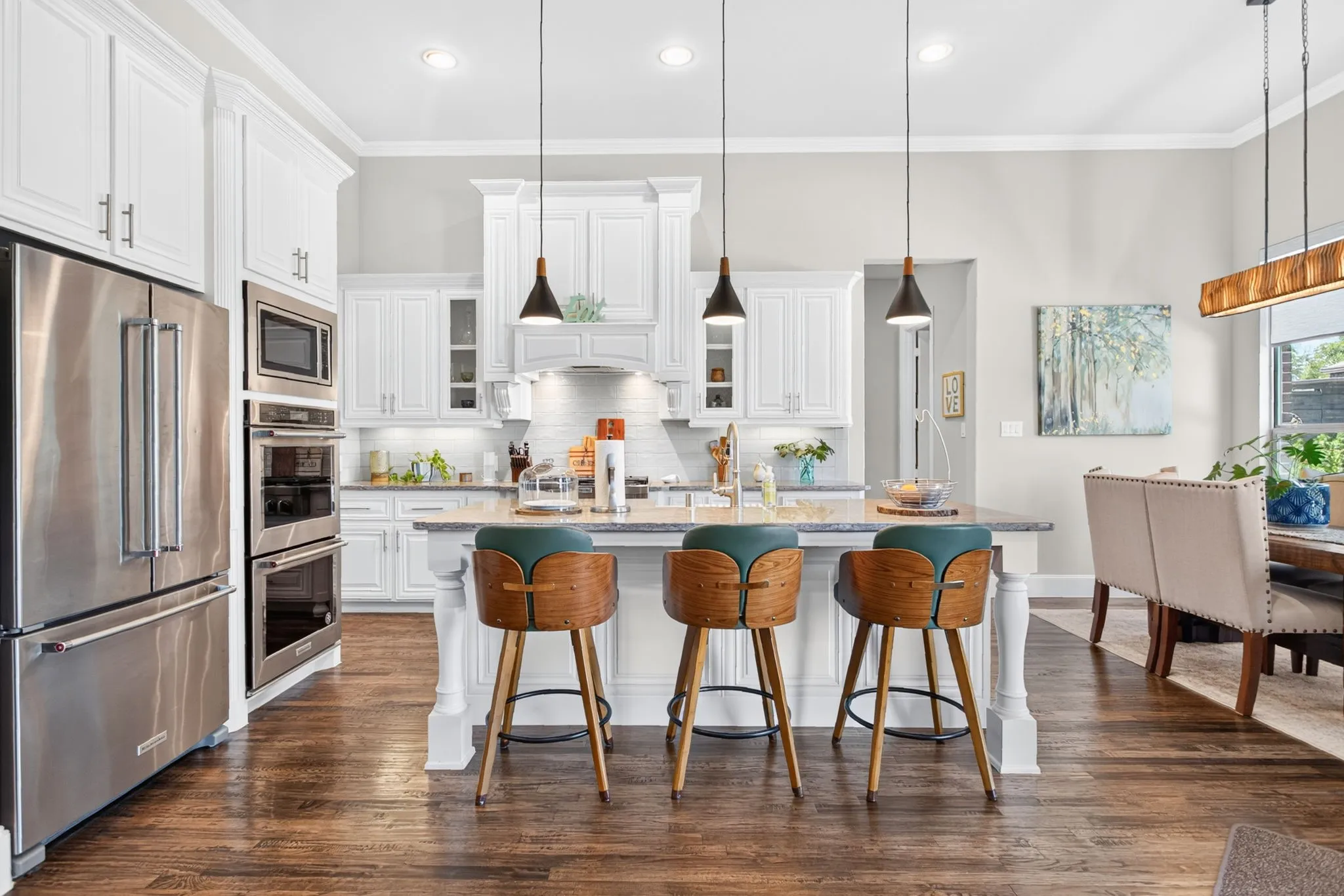 Gourmet kitchen with stainless steel appliances, a center island with pendant lighting, white cabinetry, and wood-finish flooring