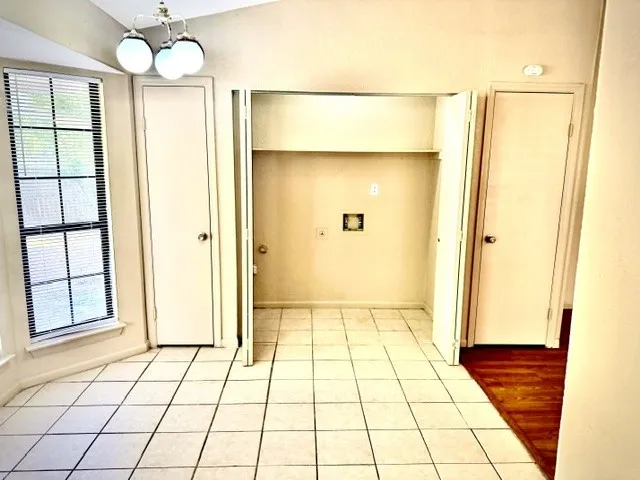 Recessed laundry area with hookups, tile flooring, and a bay window