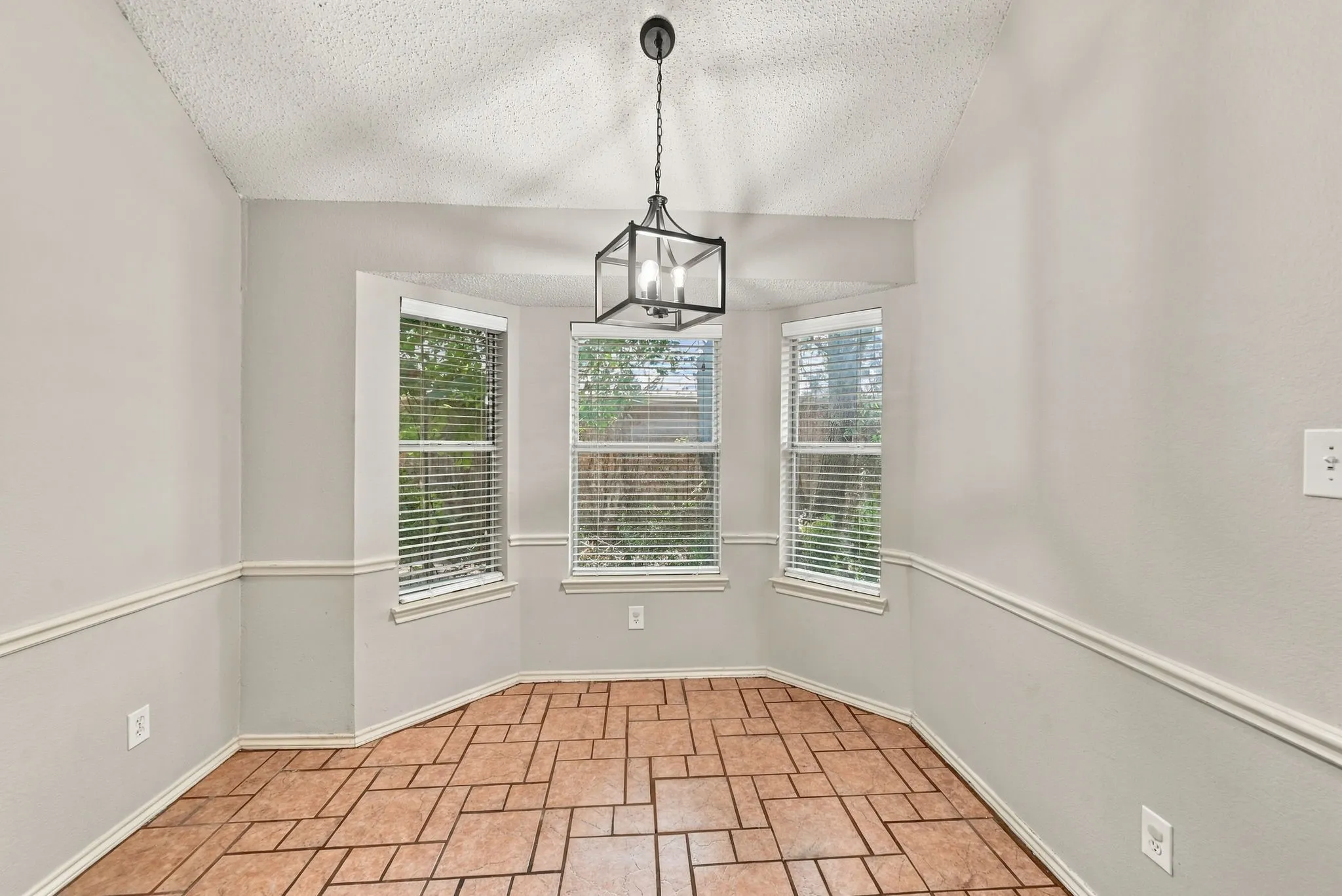 Bay window with multiple panels, geometric tile flooring, decorative wainscoting, and a contemporary chandelier