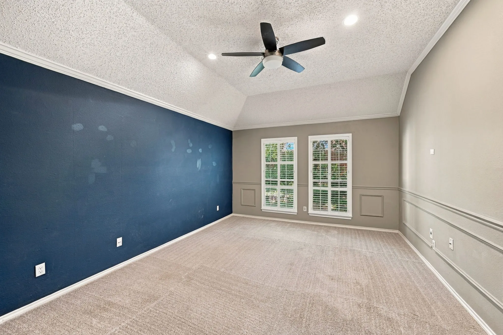 Vaulted ceiling featuring a ceiling fan, recessed lighting, crown molding, and wainscoting