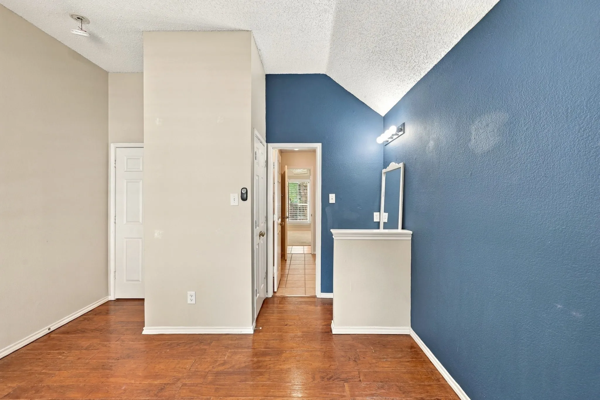 Wood-finish flooring, vaulted ceiling, recessed lighting, and a built-in vanity