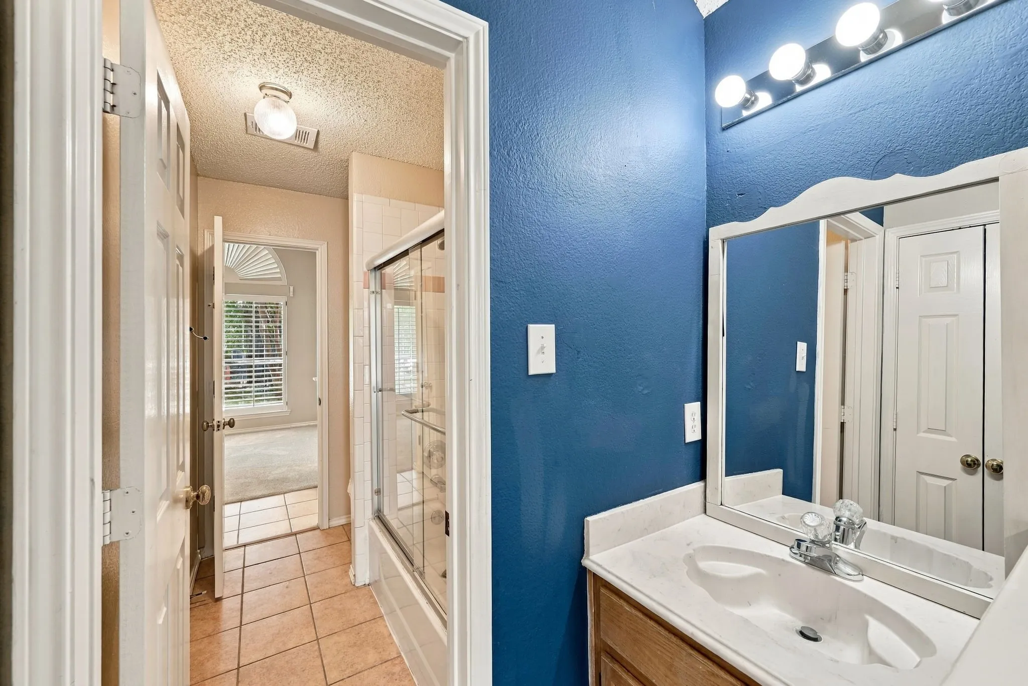 Vanity with an integrated sink, polished chrome faucet, and overhead lighting