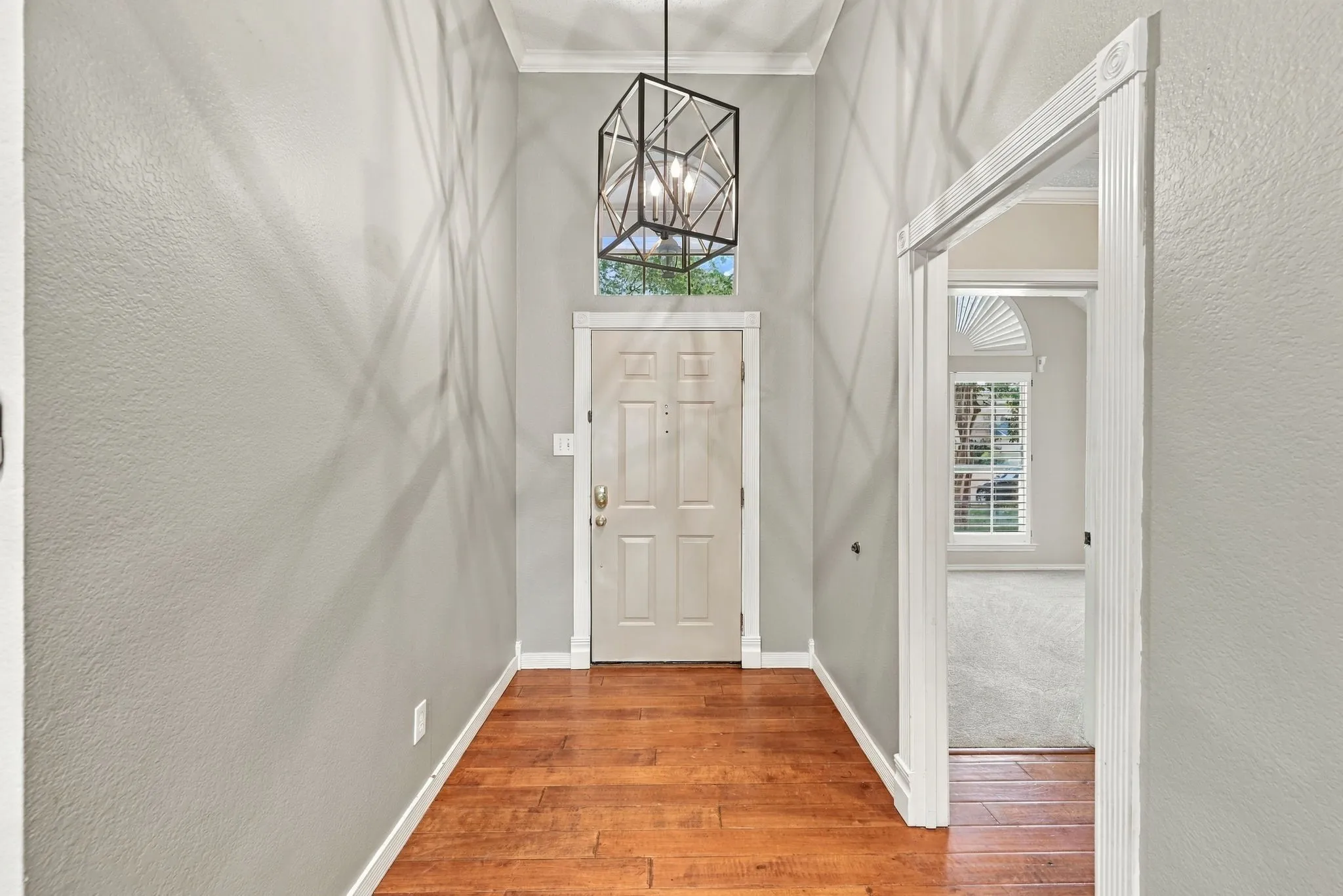 Entryway featuring wood-finish flooring, a decorative chandelier, and a transom window above the entry door