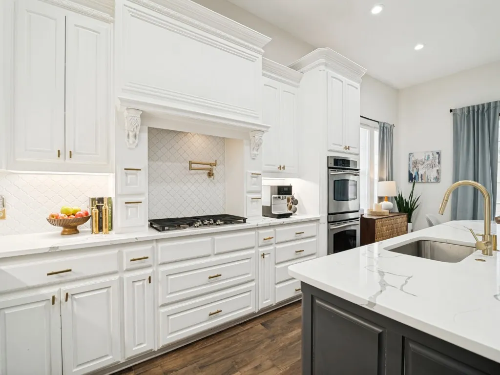 Gas cooktop, pot filler, and under-counter lighting in this bright kitchen.