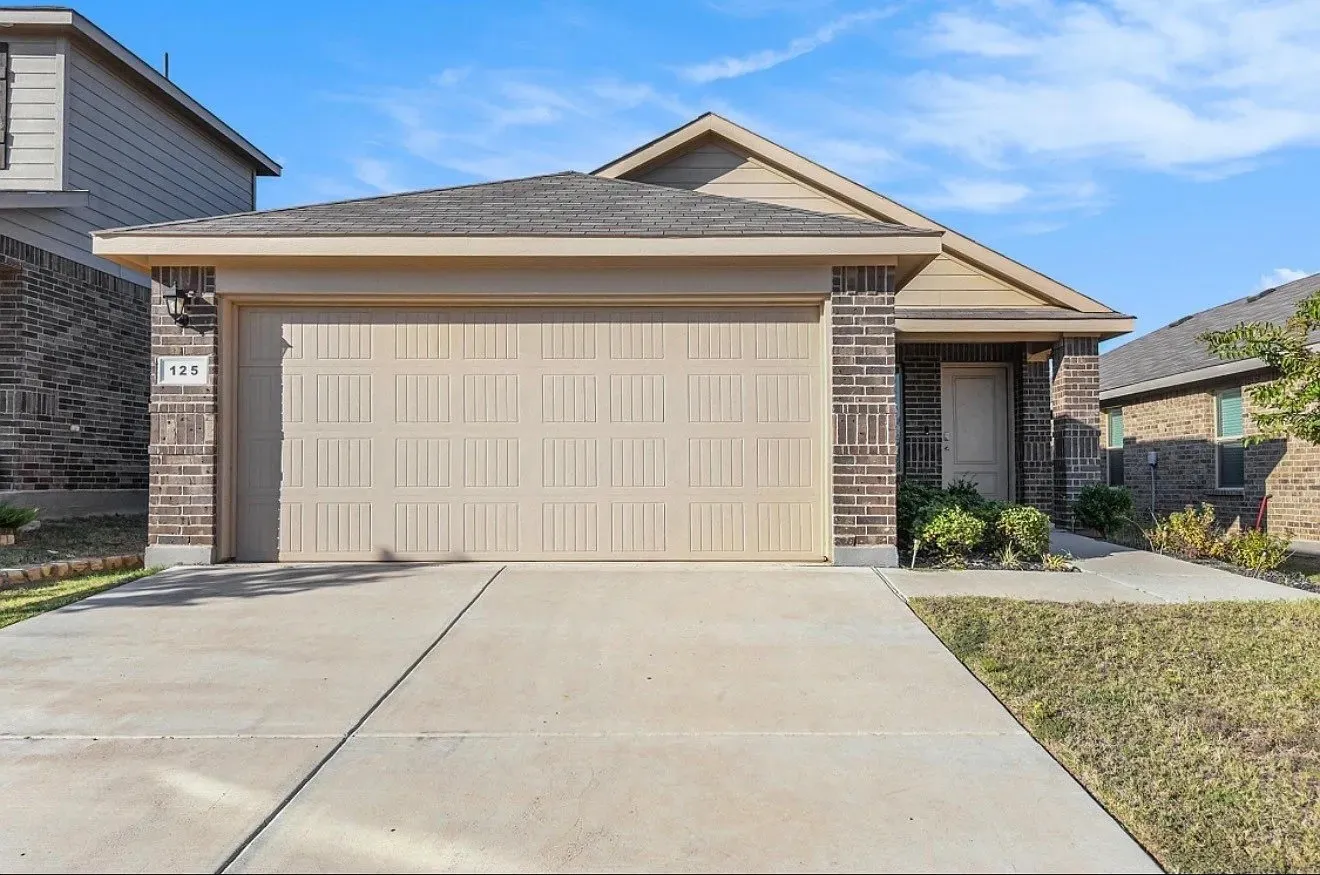 Brick and siding exterior with an attached garage, paved driveway, and concrete walkway