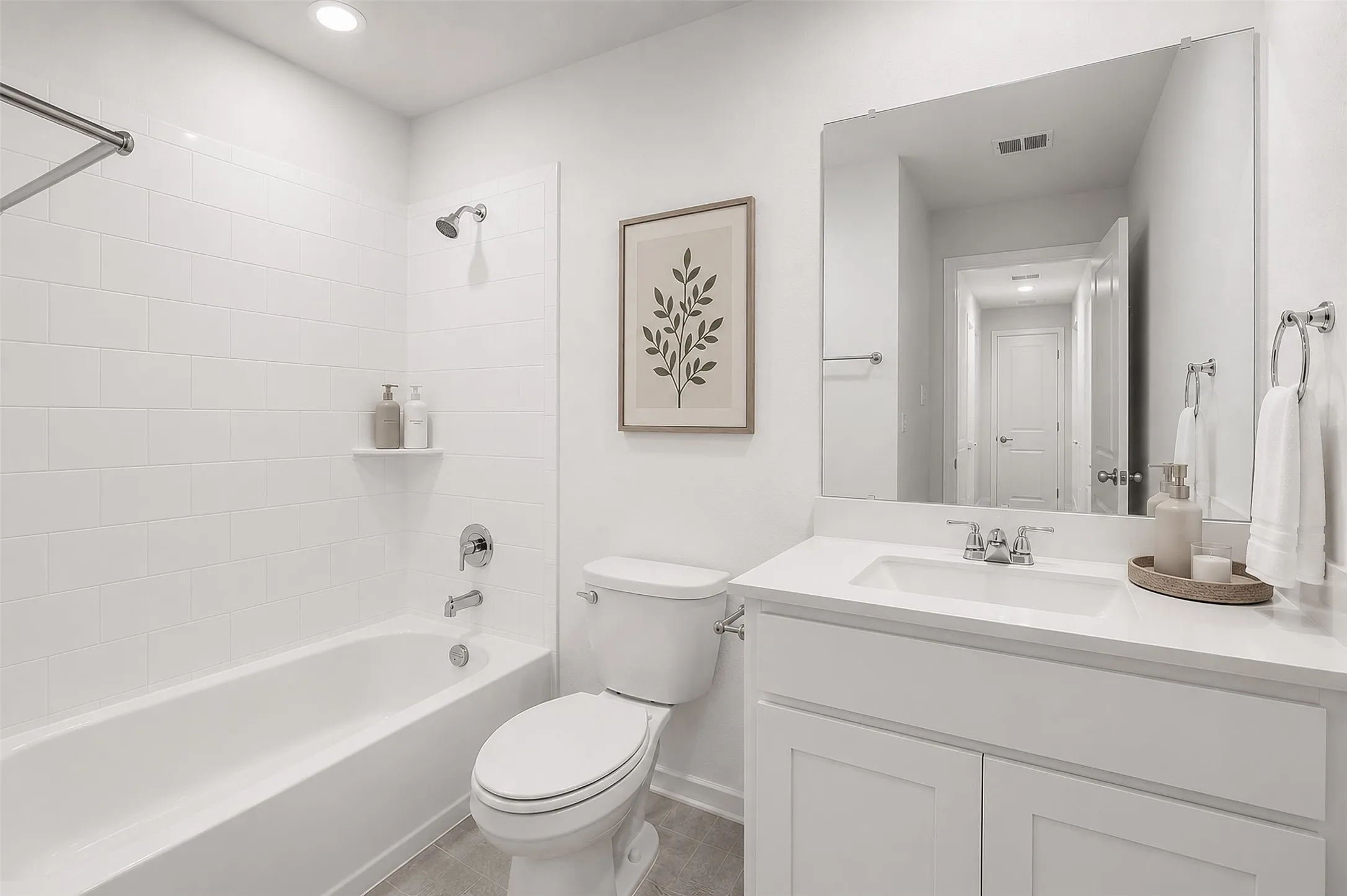 White subway tile tub surround, white vanity with integrated sink, chrome fixtures, and a large wall-mounted mirror