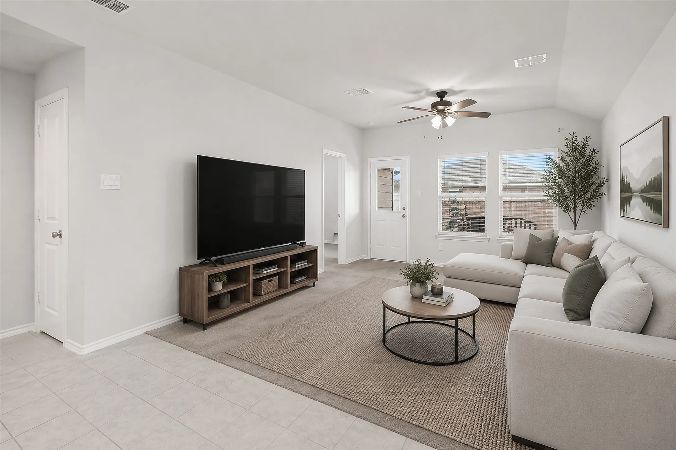 Vaulted ceiling, ceiling fan, multiple windows, tile flooring, and a white paneled door