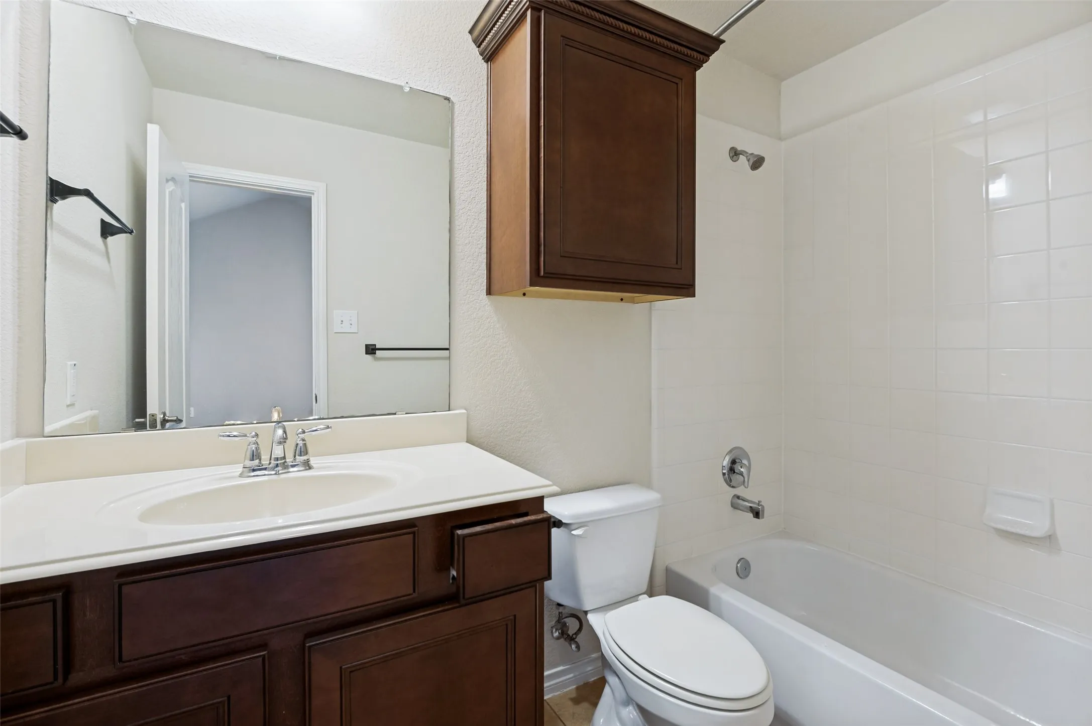 Bathroom 2 featuring a vanity with an integrated sink, polished chrome faucet, framed mirror, and a white tiled shower-tub combination