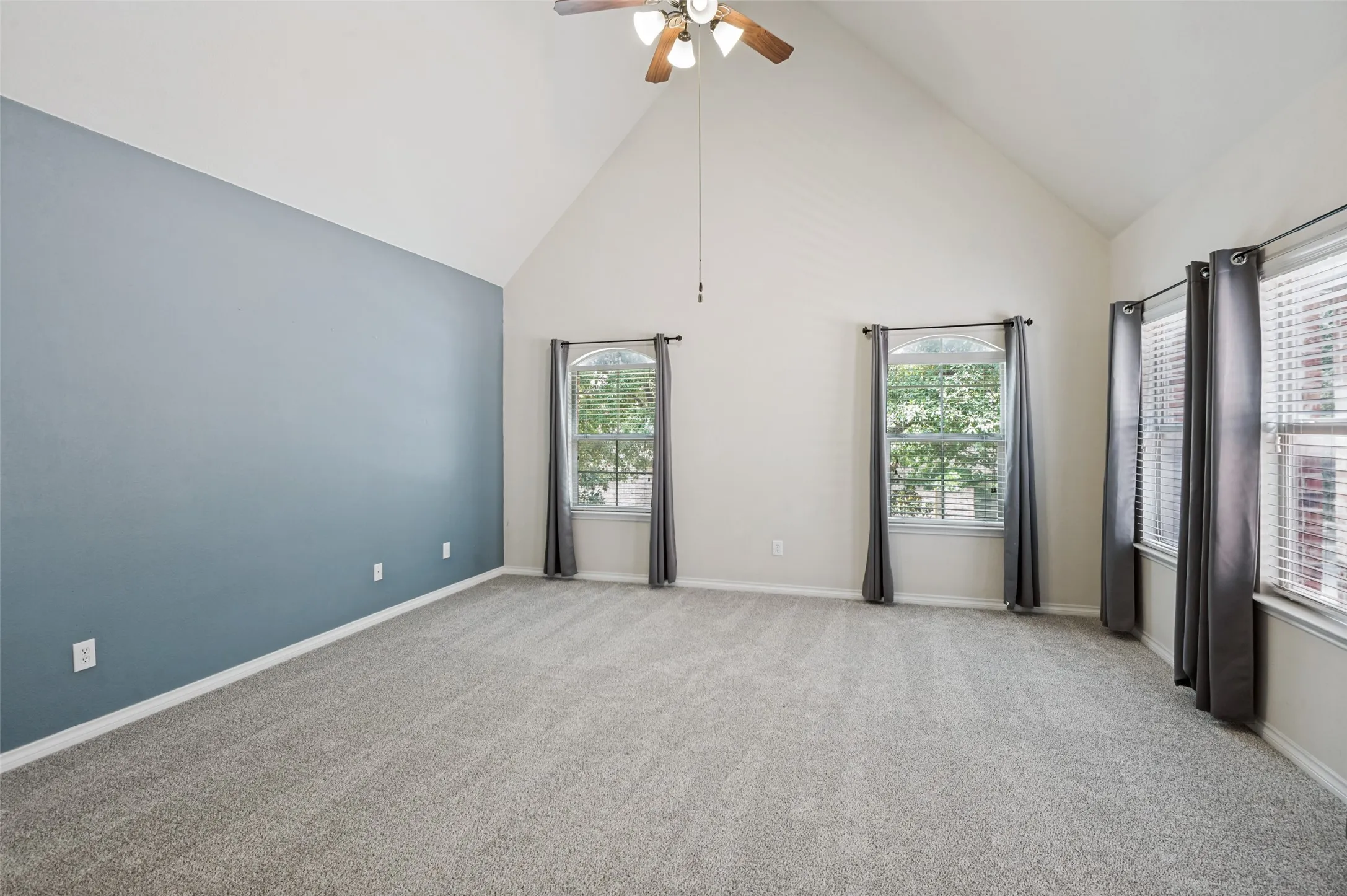 Massive Master Bedroom with vaulted ceiling with a ceiling fan, abundant natural light, gray carpeting, and an accent wall