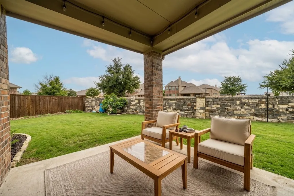 Covered patio featuring brick columns, concrete flooring, and string lighting