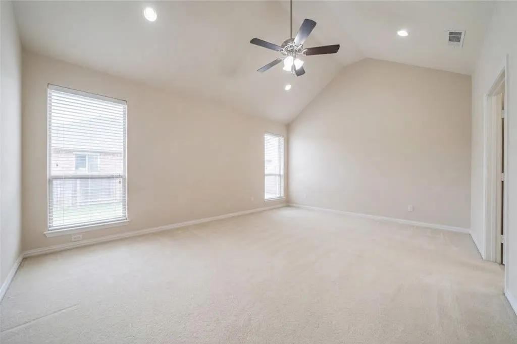 Expansive room featuring a vaulted ceiling with a ceiling fan, recessed lighting, and two windows with blinds