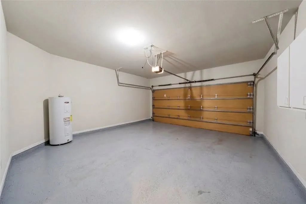 Epoxy-coated flooring, built-in water heater, overhead lighting, and wall-mounted storage cabinets