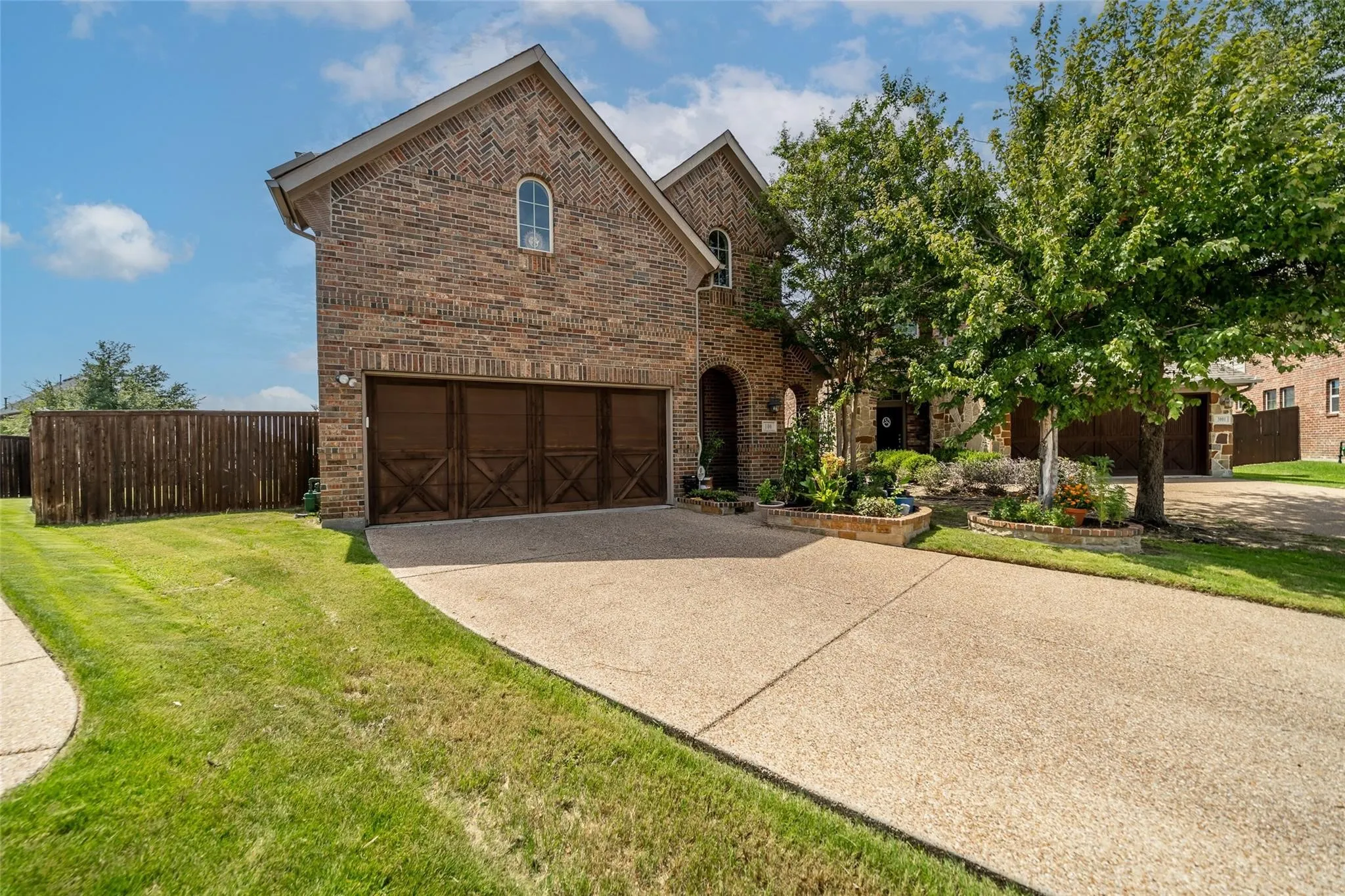 Brick exterior with a peaked roofline, arched windows, and a two-car garage with wood-finish doors