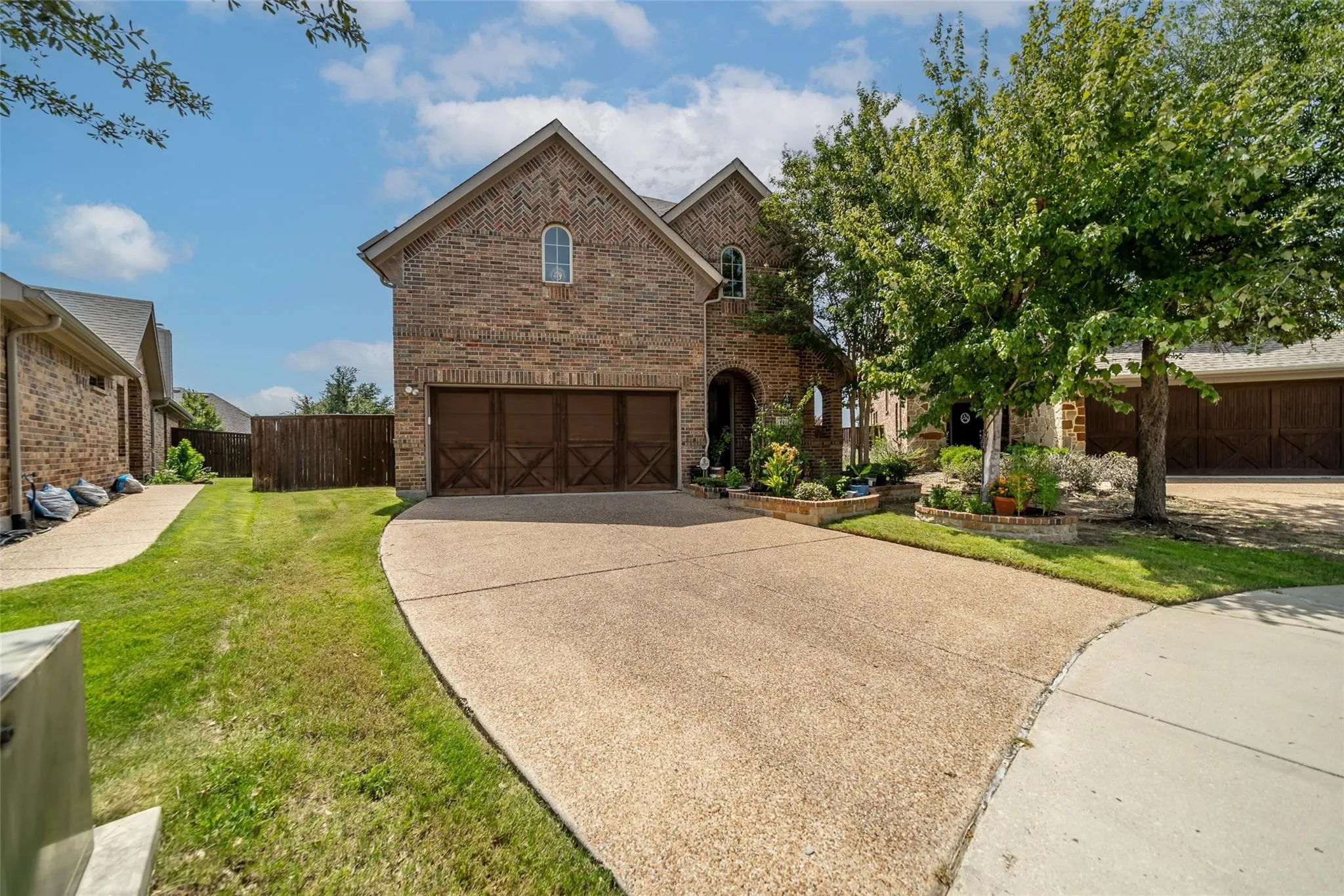 Brick exterior with arched windows, an attached two-car garage, and a concrete driveway