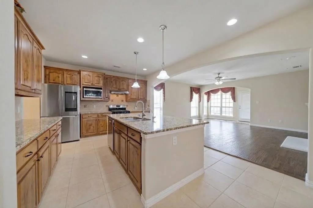 Gourmet kitchen with wood cabinetry, granite countertops, stainless steel appliances, and a central island