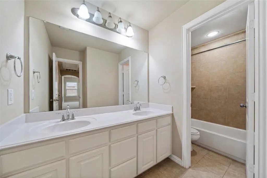 Dual sink vanity with white cabinetry and a large wall-mounted mirror