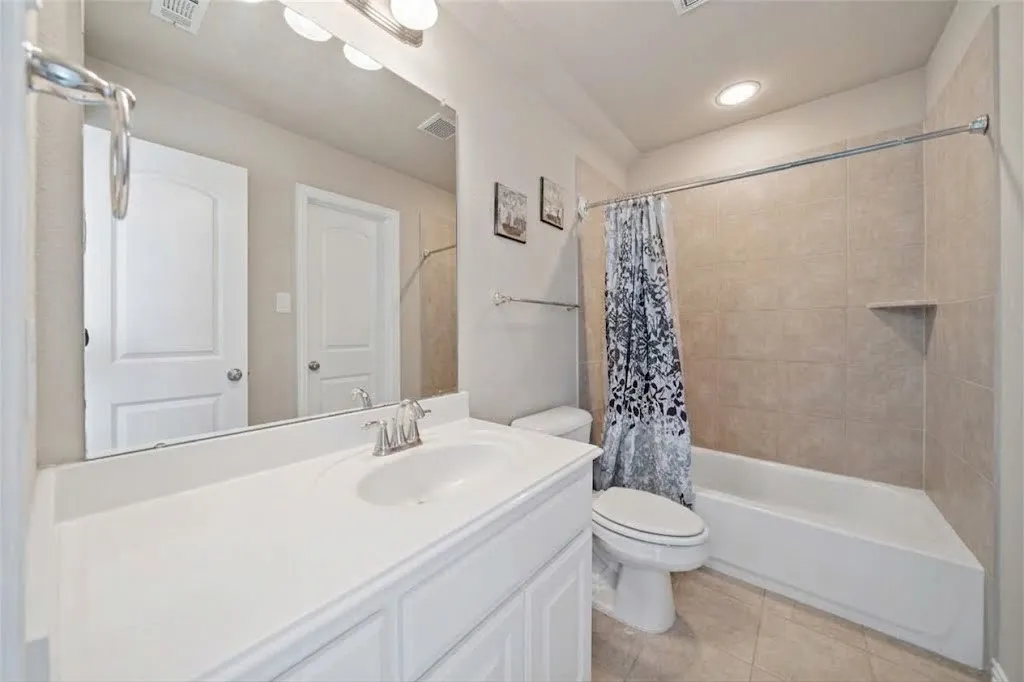 White vanity with integrated sink and chrome faucet, large frameless mirror, and overhead vanity lighting