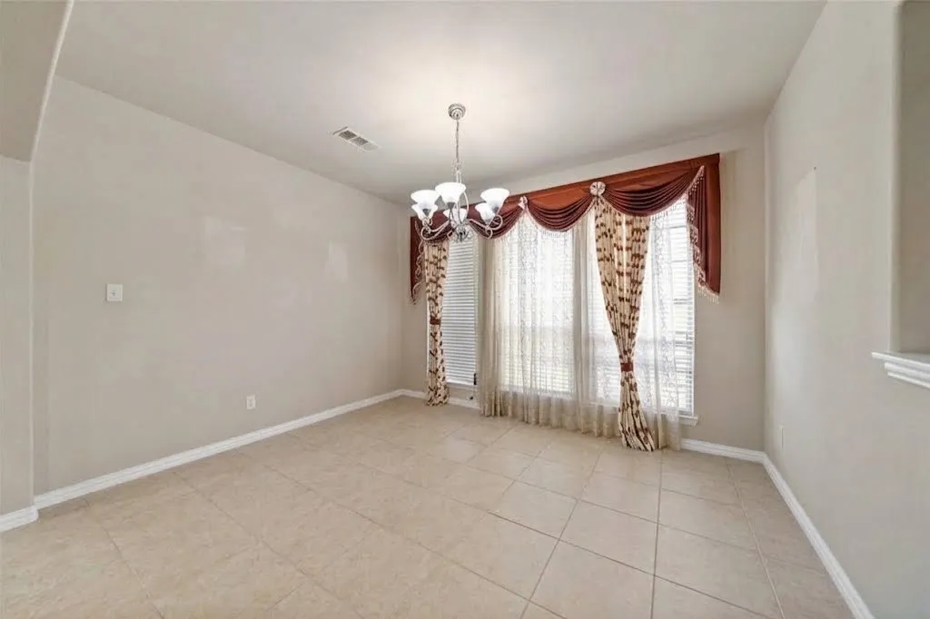Tile flooring, neutral wall tones, elegant chandelier, large window, decorative window treatments