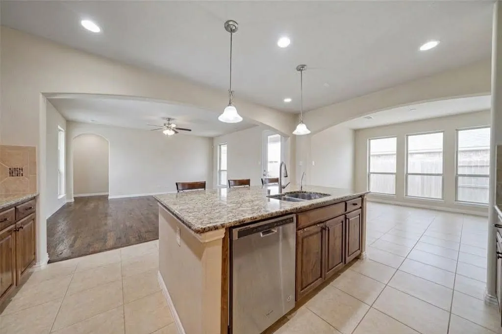 Kitchen island featuring a double-basin sink, stainless steel dishwasher, and pendant lighting