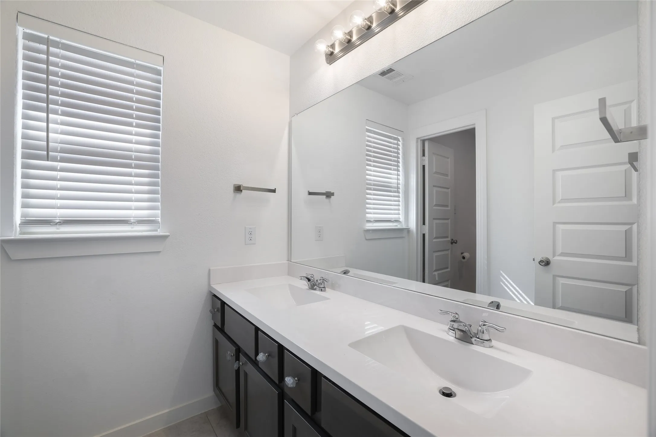 Dual basin vanity with a light-toned countertop, undermount sinks, and chrome fixtures