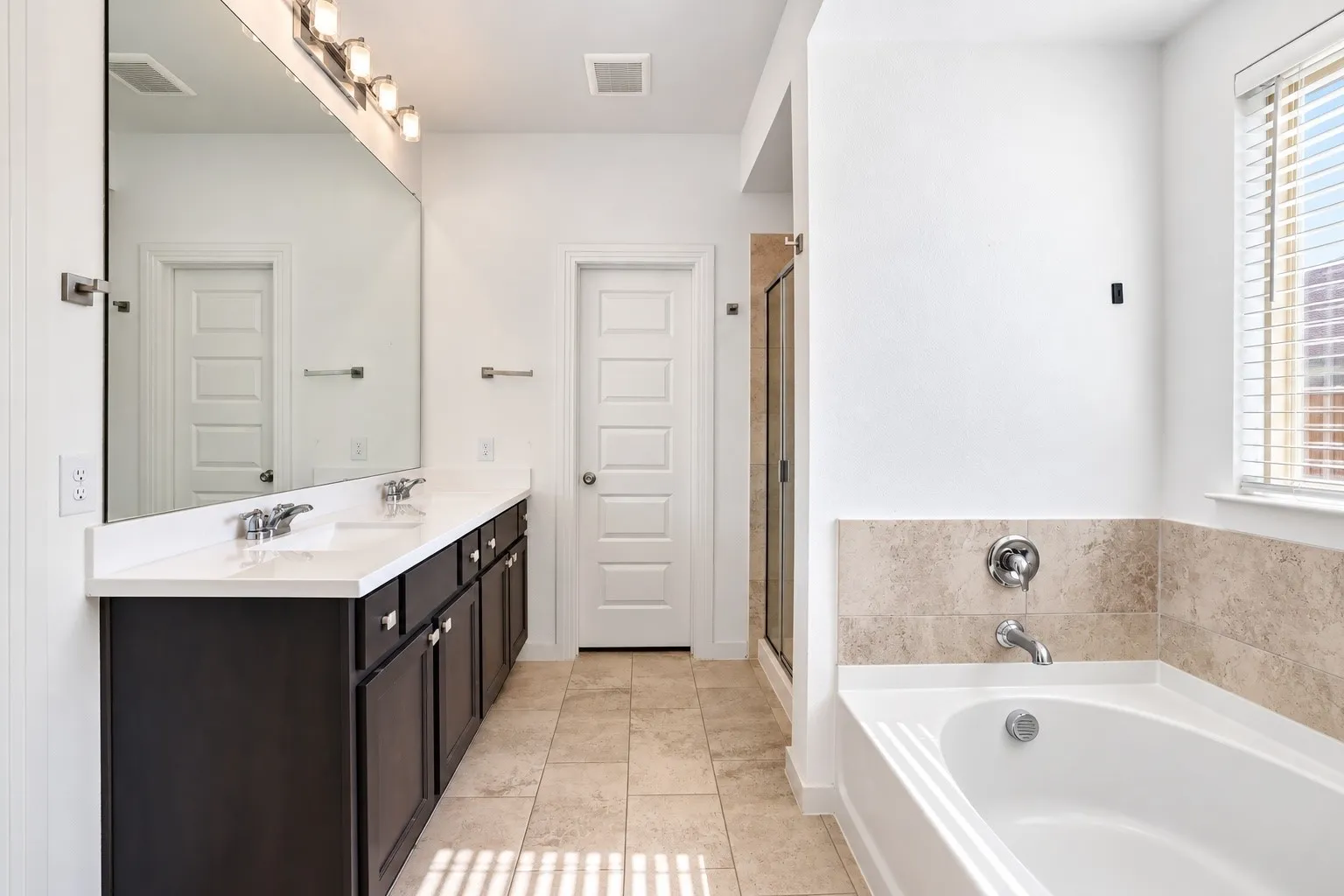 Dual sink vanity with dark wood-finish cabinetry, a white countertop, and chrome fixtures