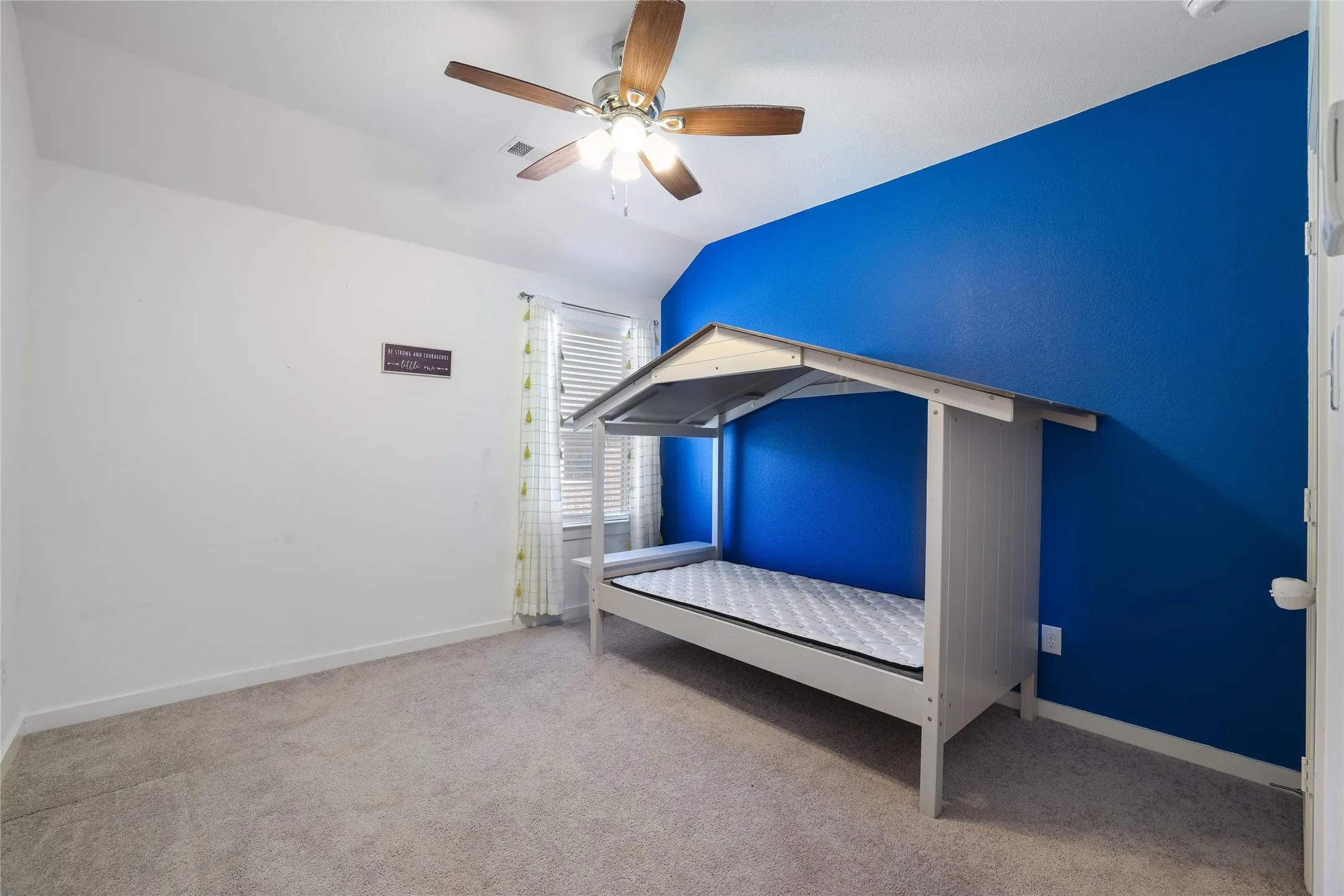 Carpeted room with a ceiling fan, a window with blinds, and a contrasting accent wall