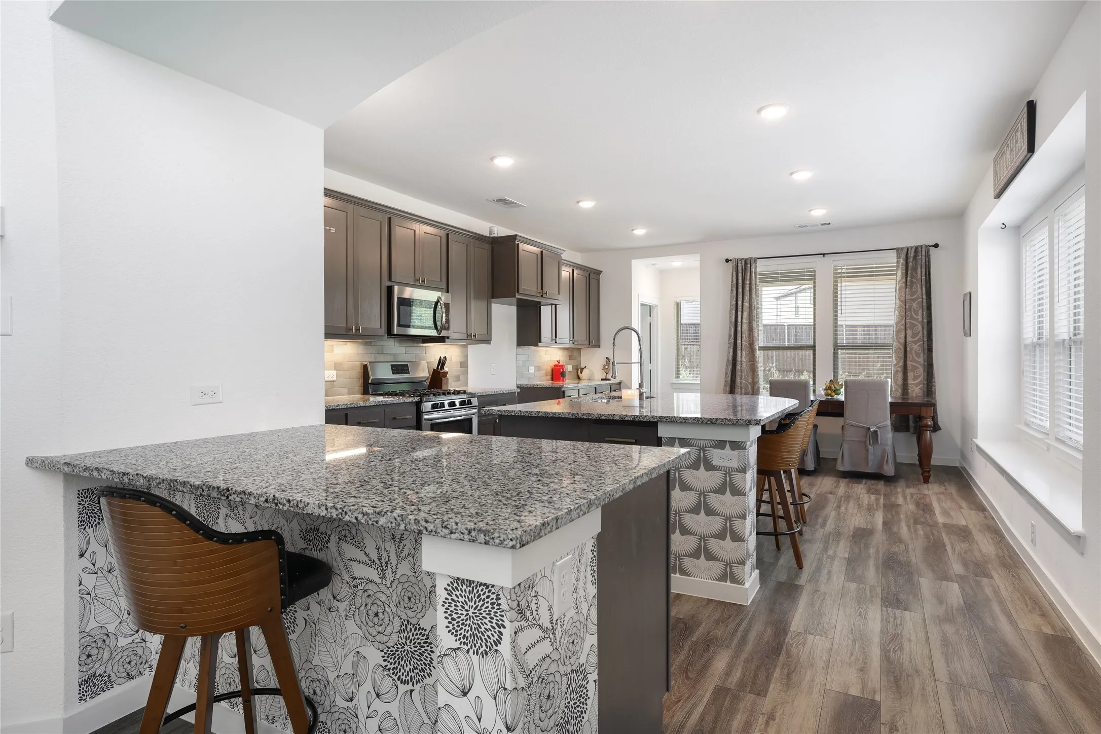 Gourmet kitchen featuring granite countertops, dark wood cabinetry, stainless steel appliances, and wood-finish flooring