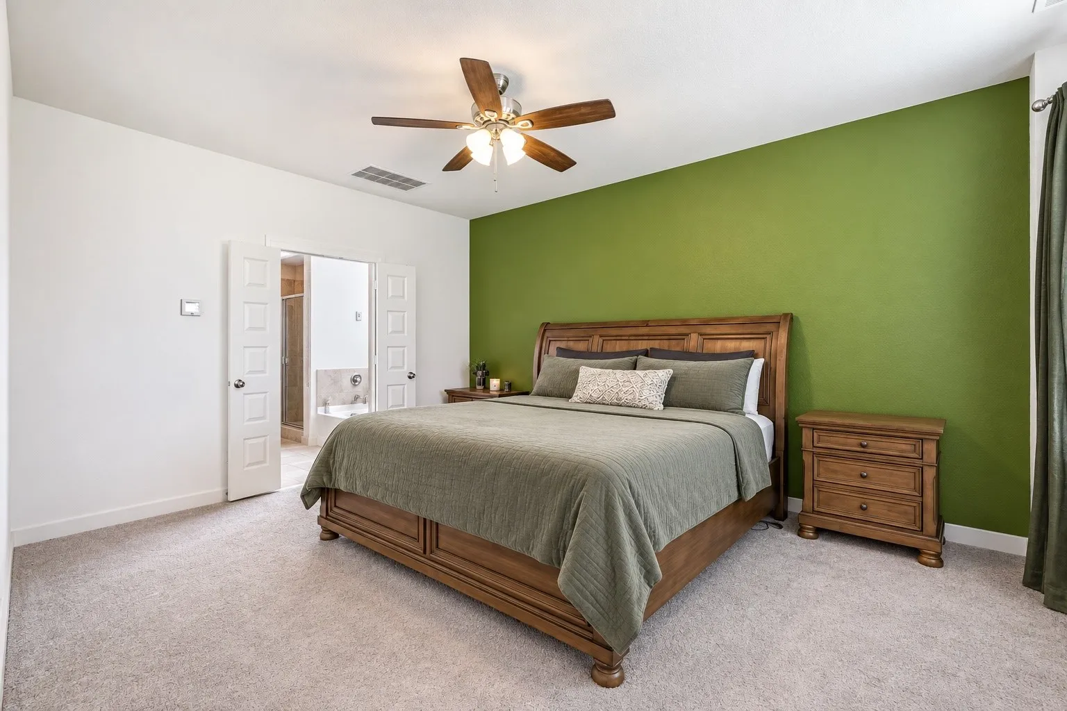 Recessed lighting, ceiling fan with light fixture, carpeted flooring, French doors, and an open doorway reveal a bathroom with a tub and shower