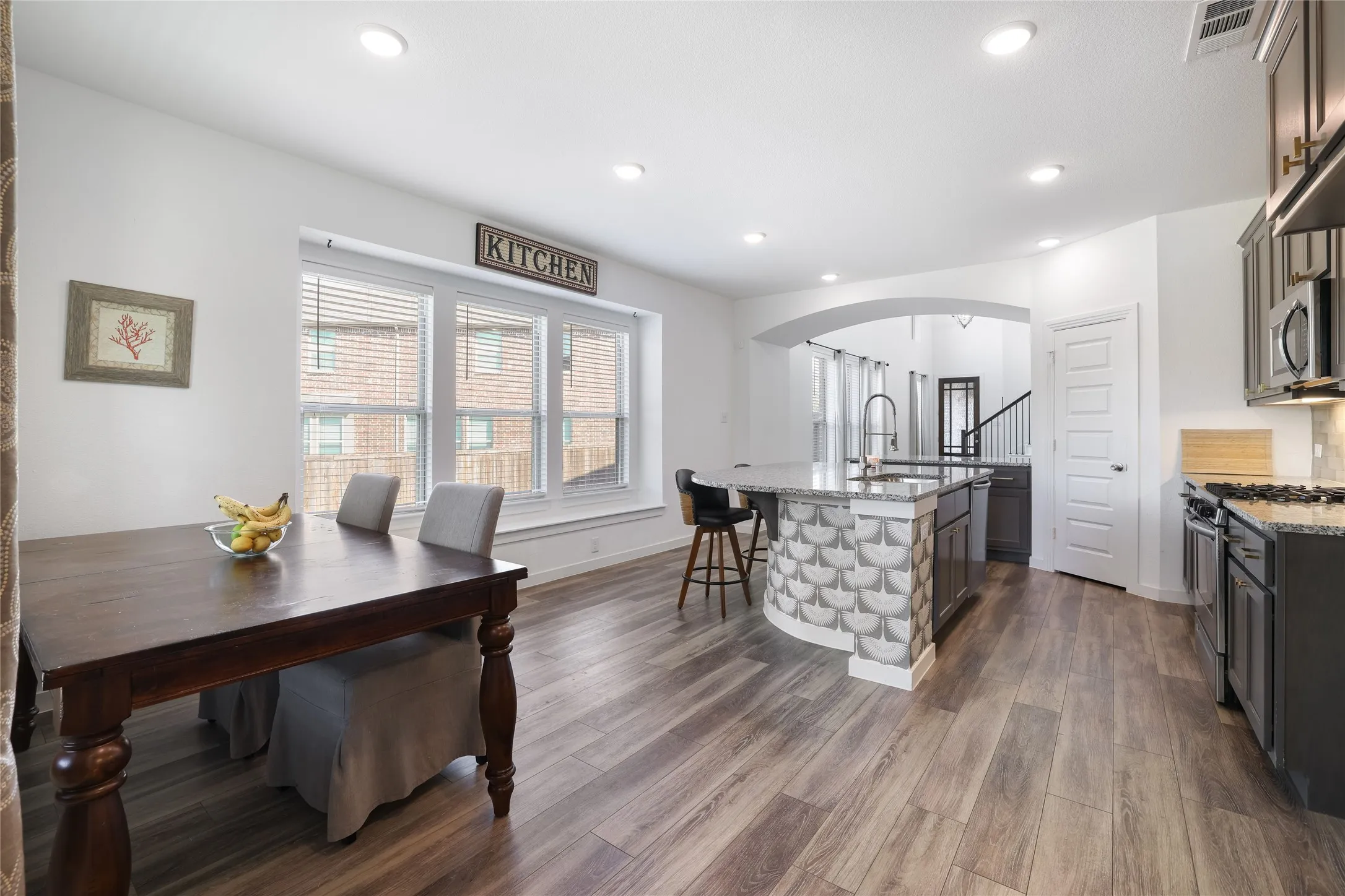 Open-concept kitchen featuring wood-finish flooring, recessed lighting, a kitchen island with seating, and stainless steel appliances