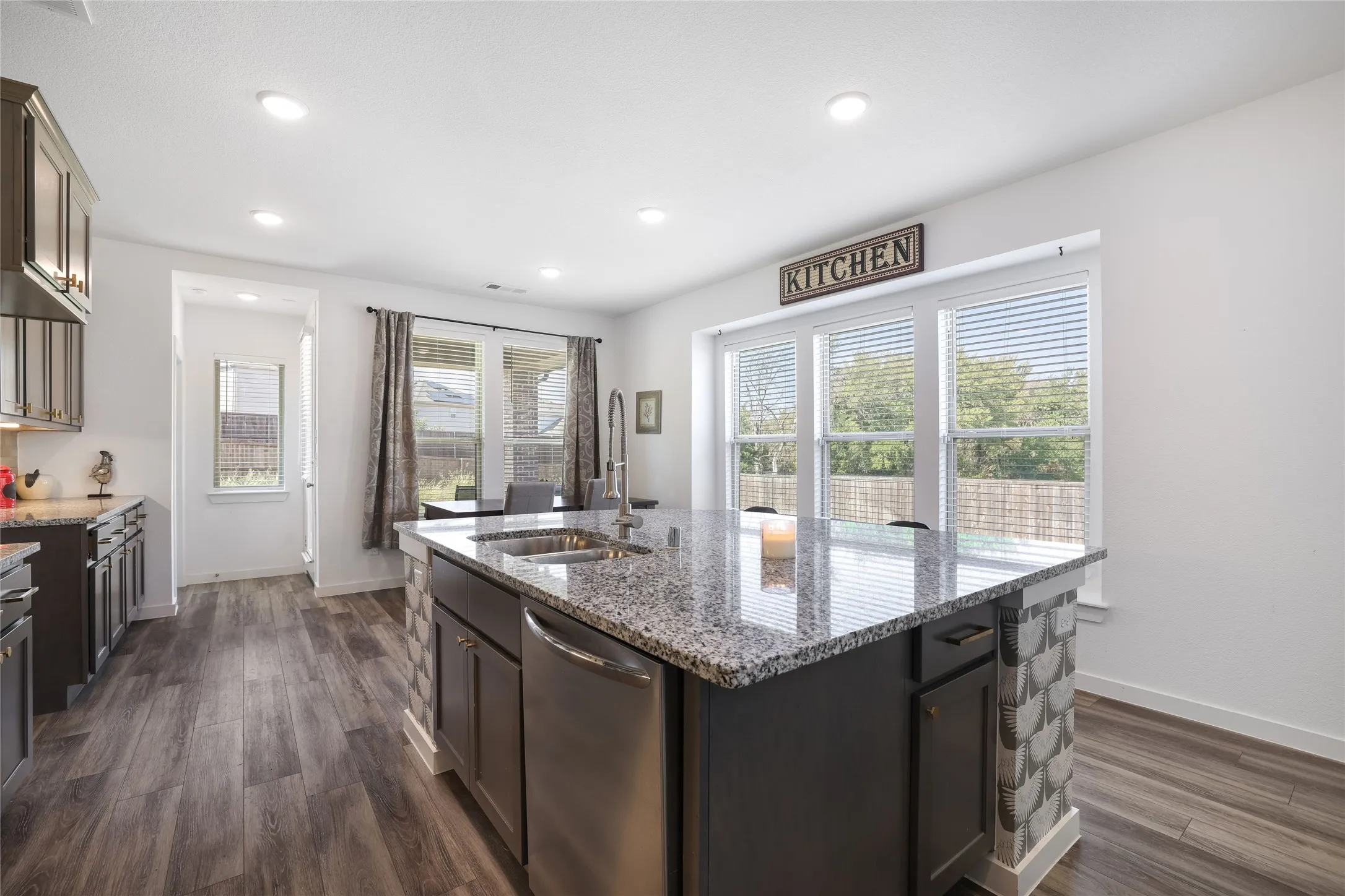 Kitchen featuring an expansive island with a double basin sink, stainless steel dishwasher, and stone countertop