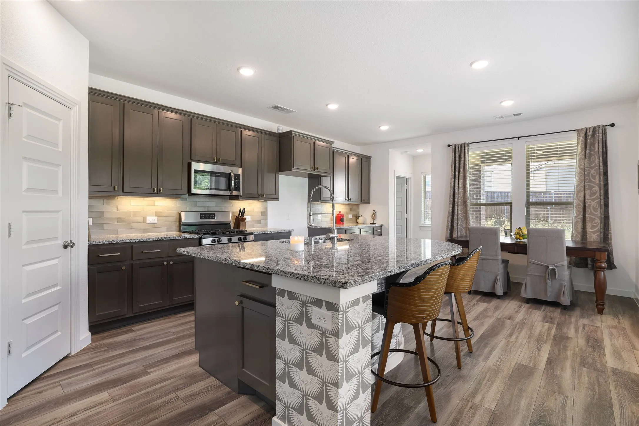 Kitchen featuring dark wood cabinetry, stainless steel appliances, granite countertops, and wood-finish flooring
