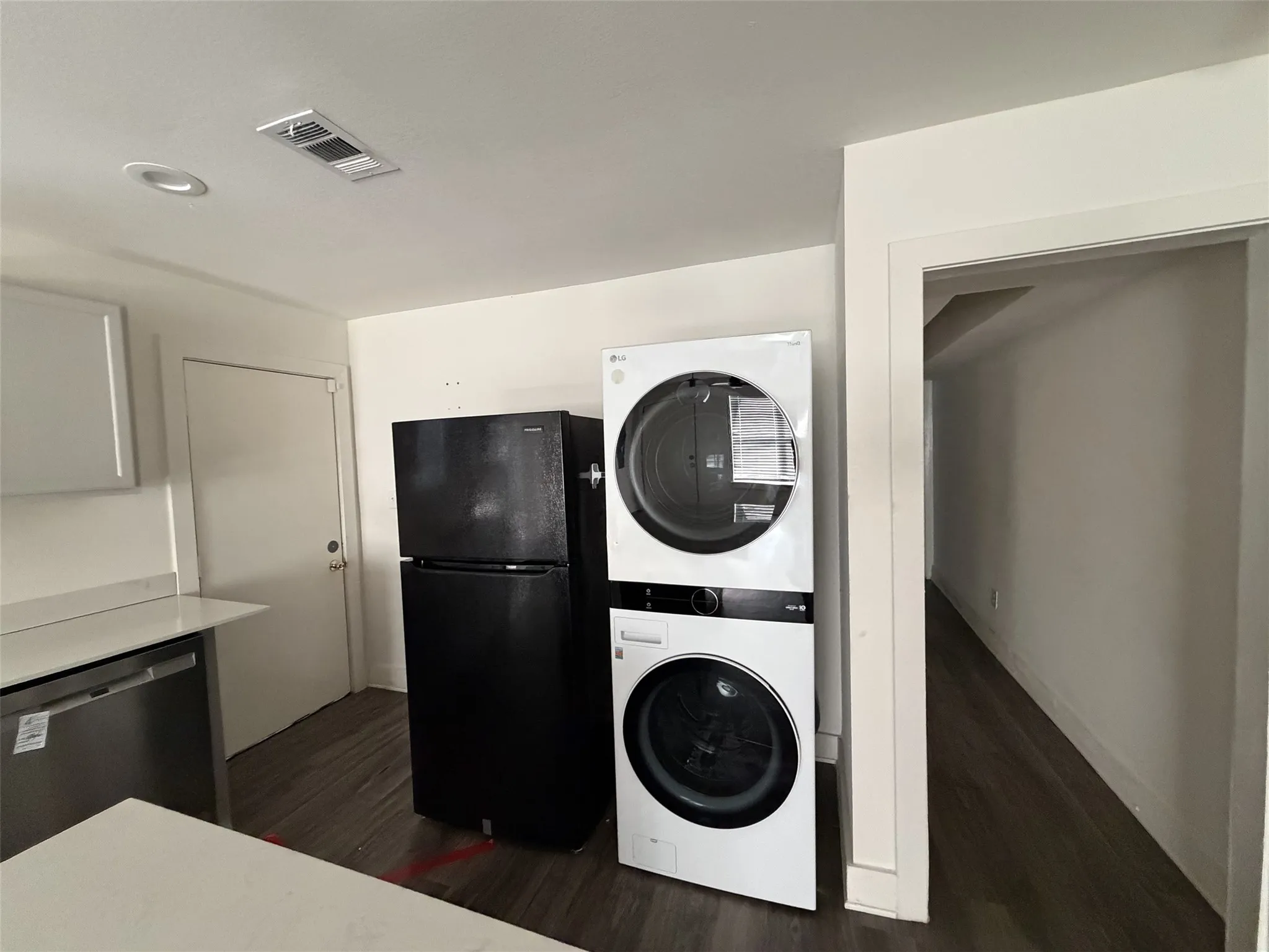 Utility in kitchen with stackable and fridge.