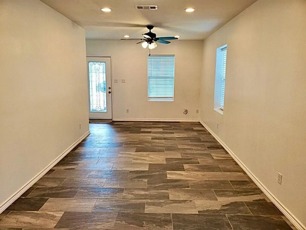 Rectangular tile flooring with varied tones, ceiling fan with light fixture, recessed lighting, and a window with horizontal blinds