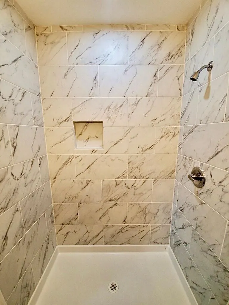 Shower with full-height tile surround, integrated shower niche, and a white shower base