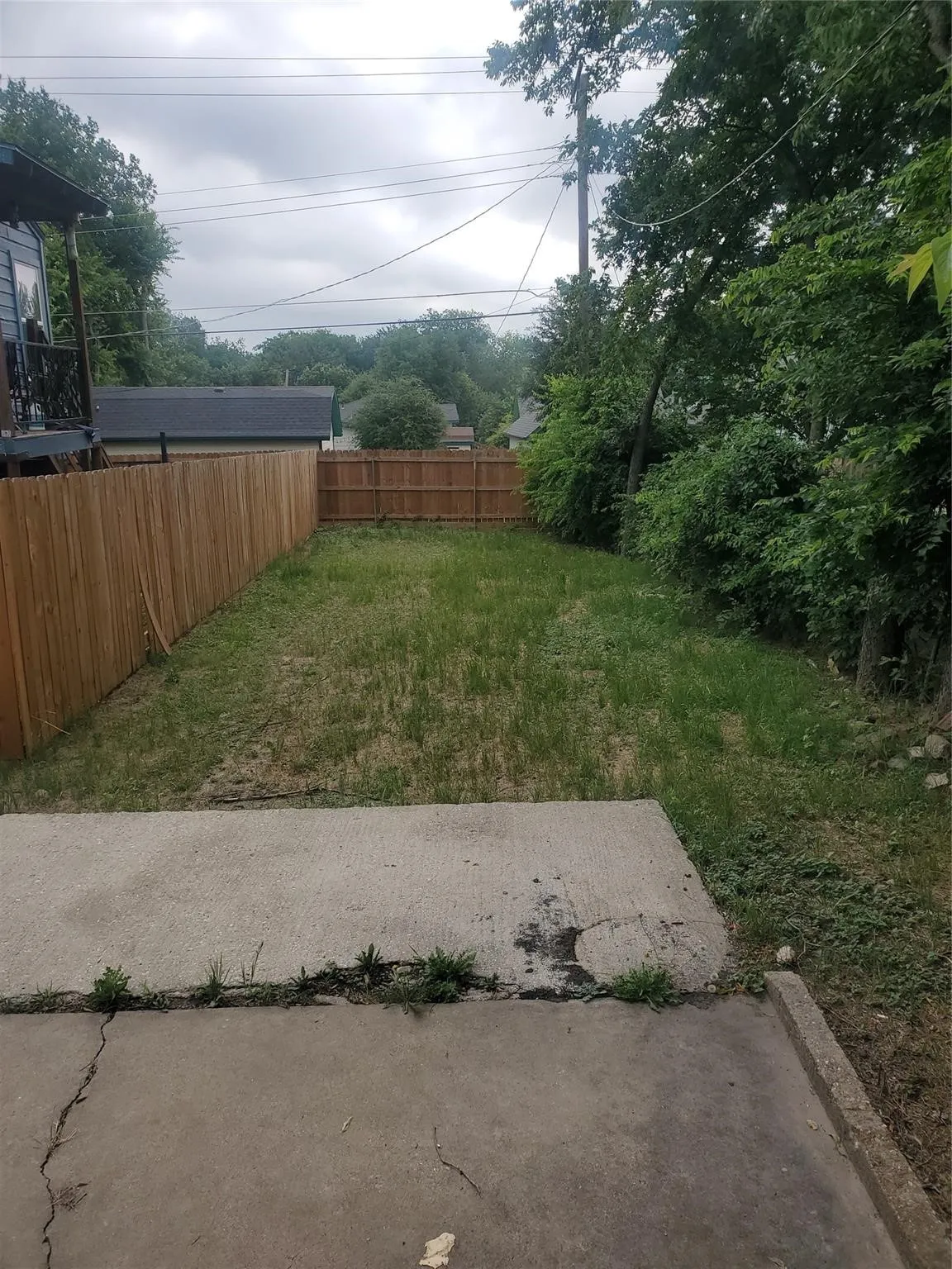 Fenced backyard with concrete patio