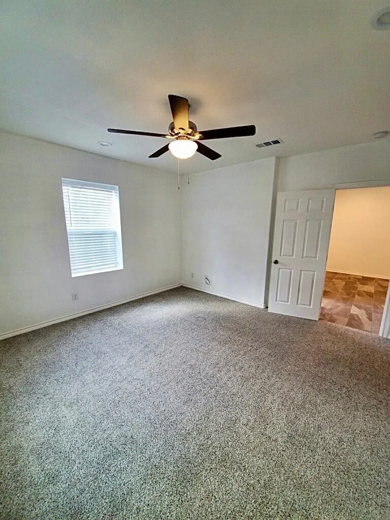 Carpeted room featuring a ceiling fan with integrated lighting, a window with blinds, and white interior doors