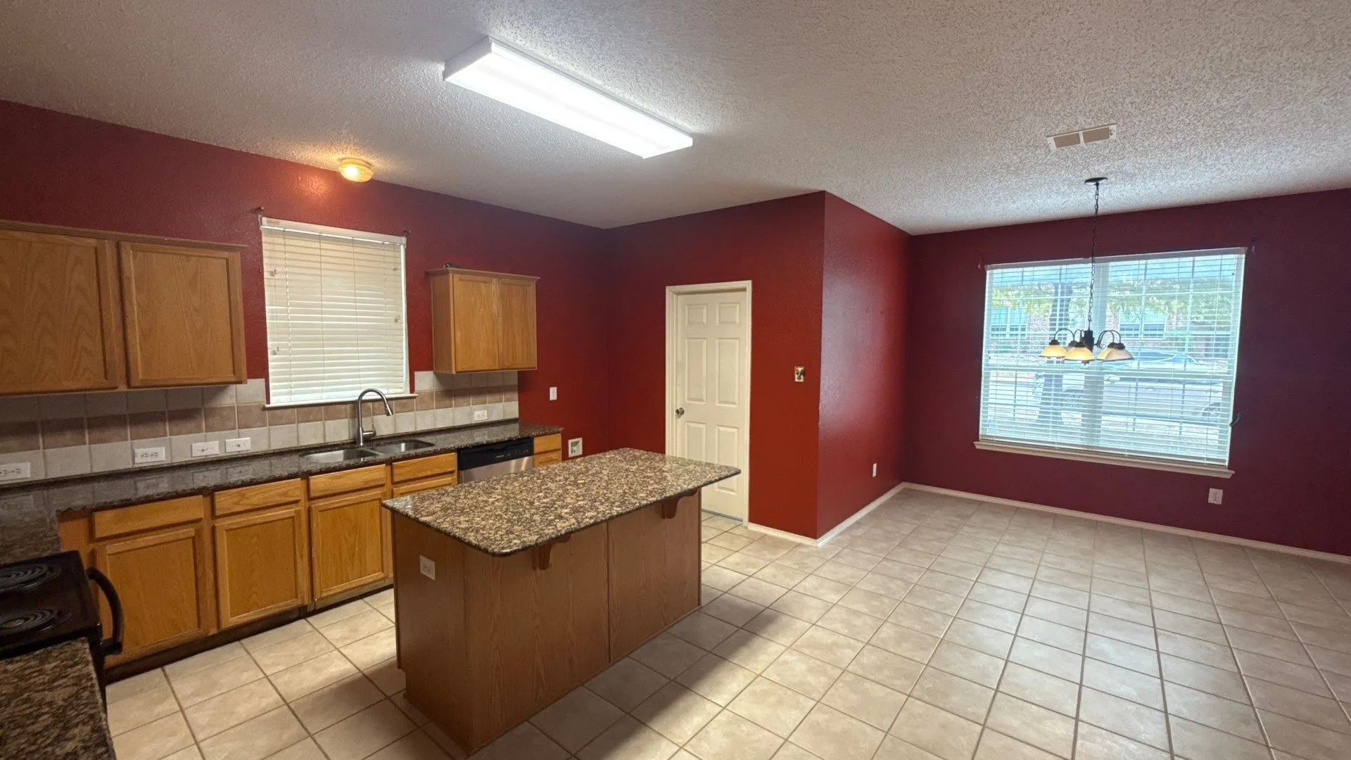 Kitchen featuring wood cabinetry, stone countertops, a central island, and tile flooring