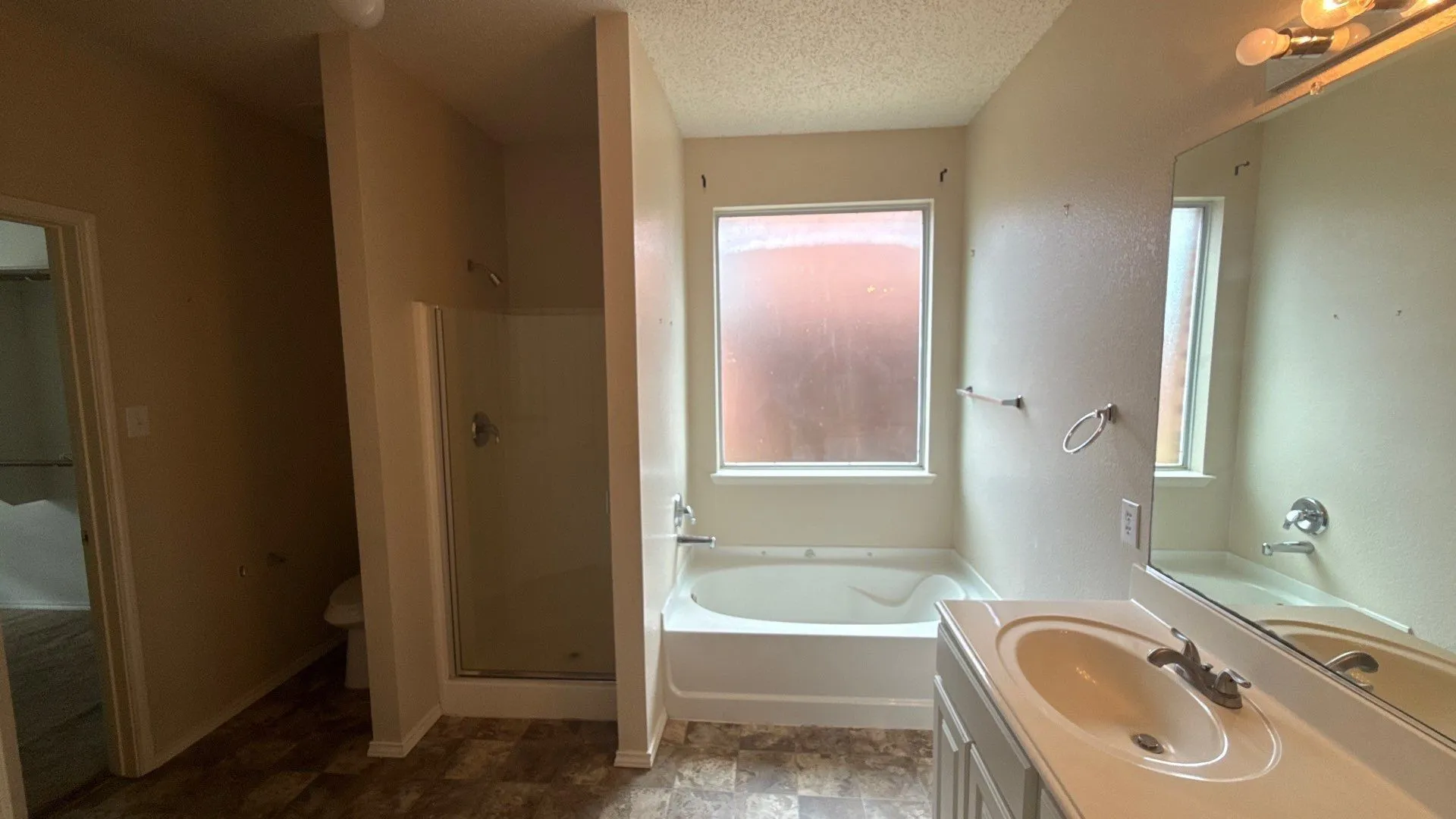 Bathroom featuring a single vanity, large mirror, enclosed shower, built-in bathtub, and window