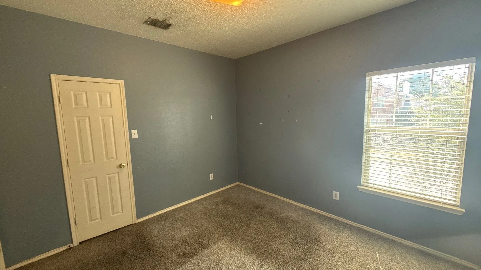 Window with blinds, wall-to-wall carpeting, and a six-panel door