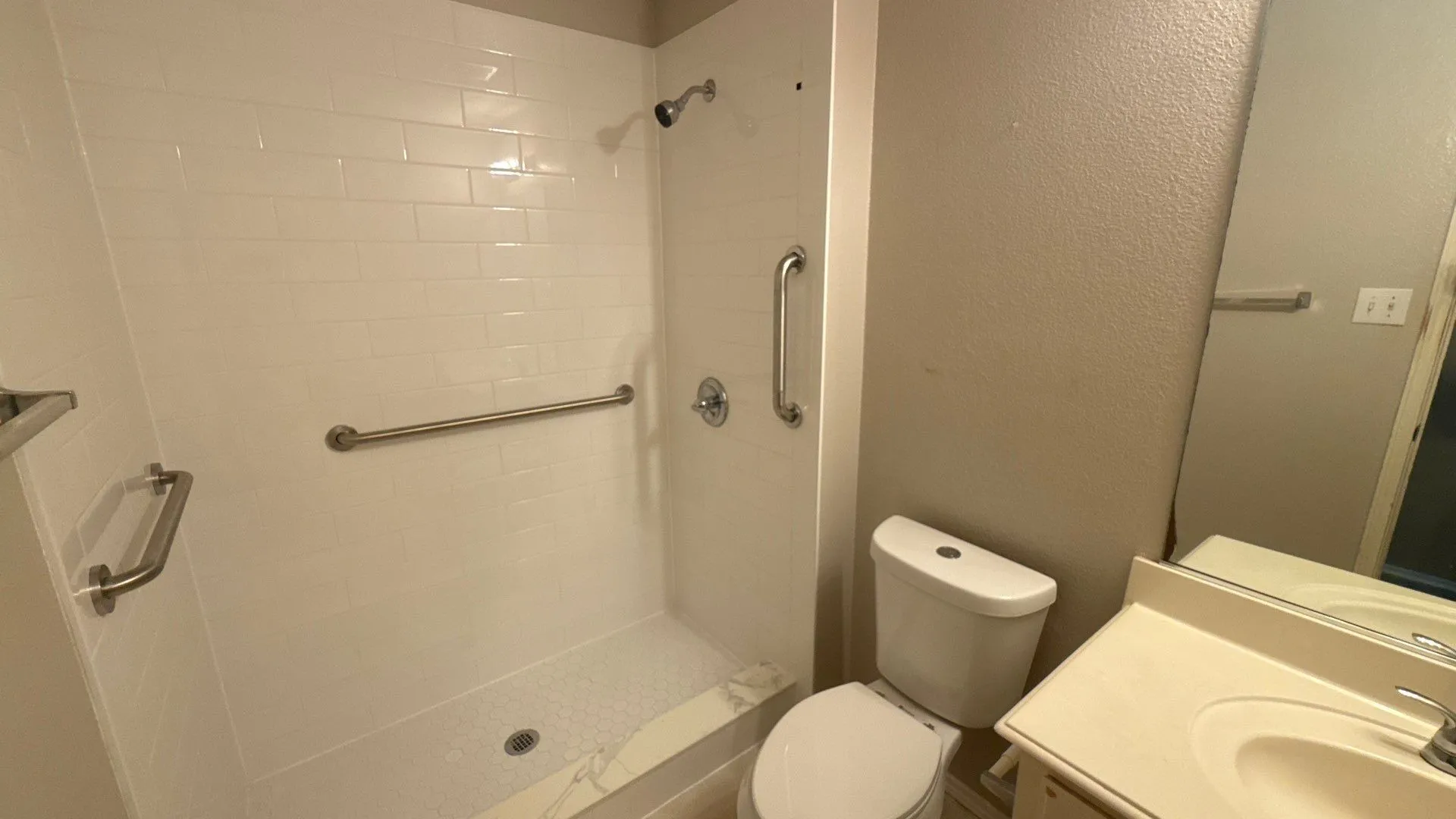 Shower with white subway tile surround, integrated shower base, and grab bars