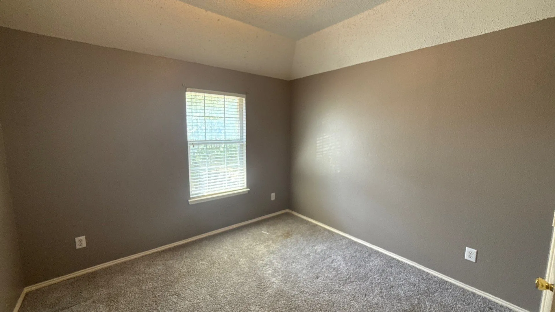 Recessed ceiling detail over neutral-toned walls, textured ceiling, and a window with blinds
