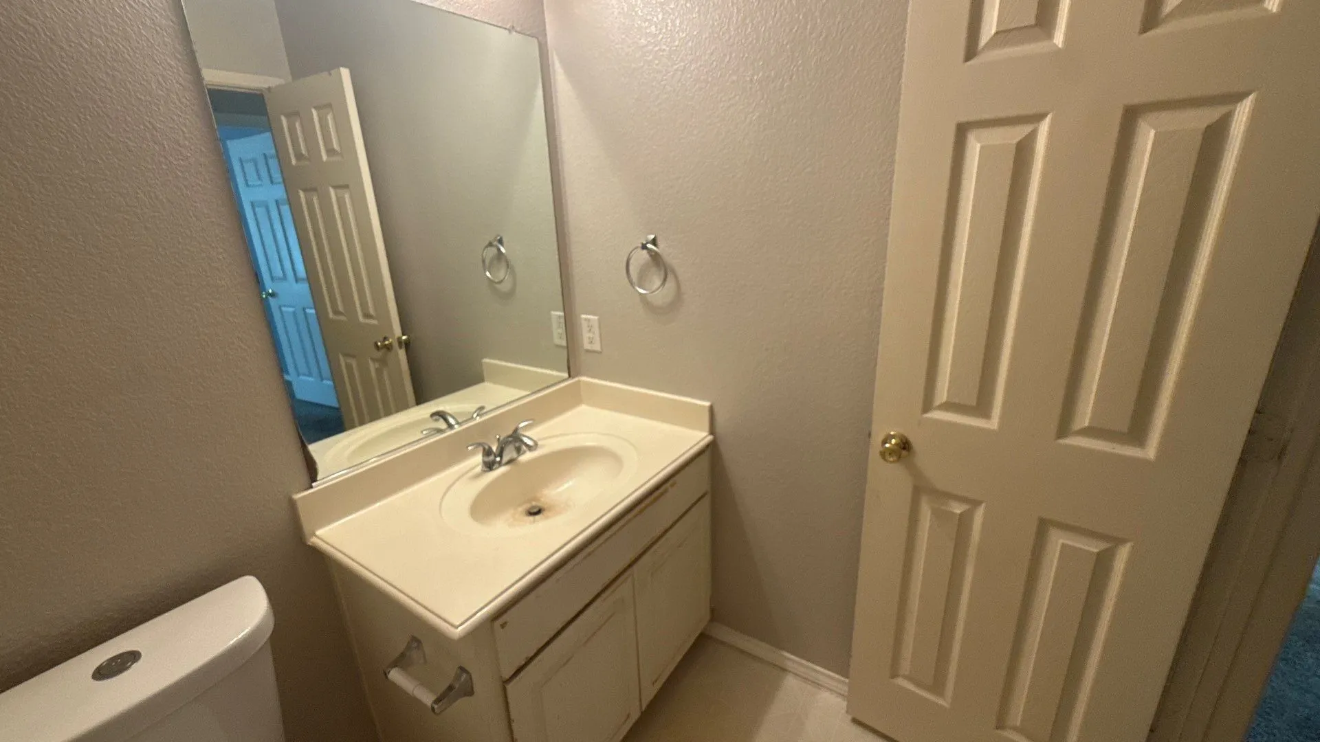 Vanity with an integrated sink and chrome faucet, set beneath a large wall-mounted mirror