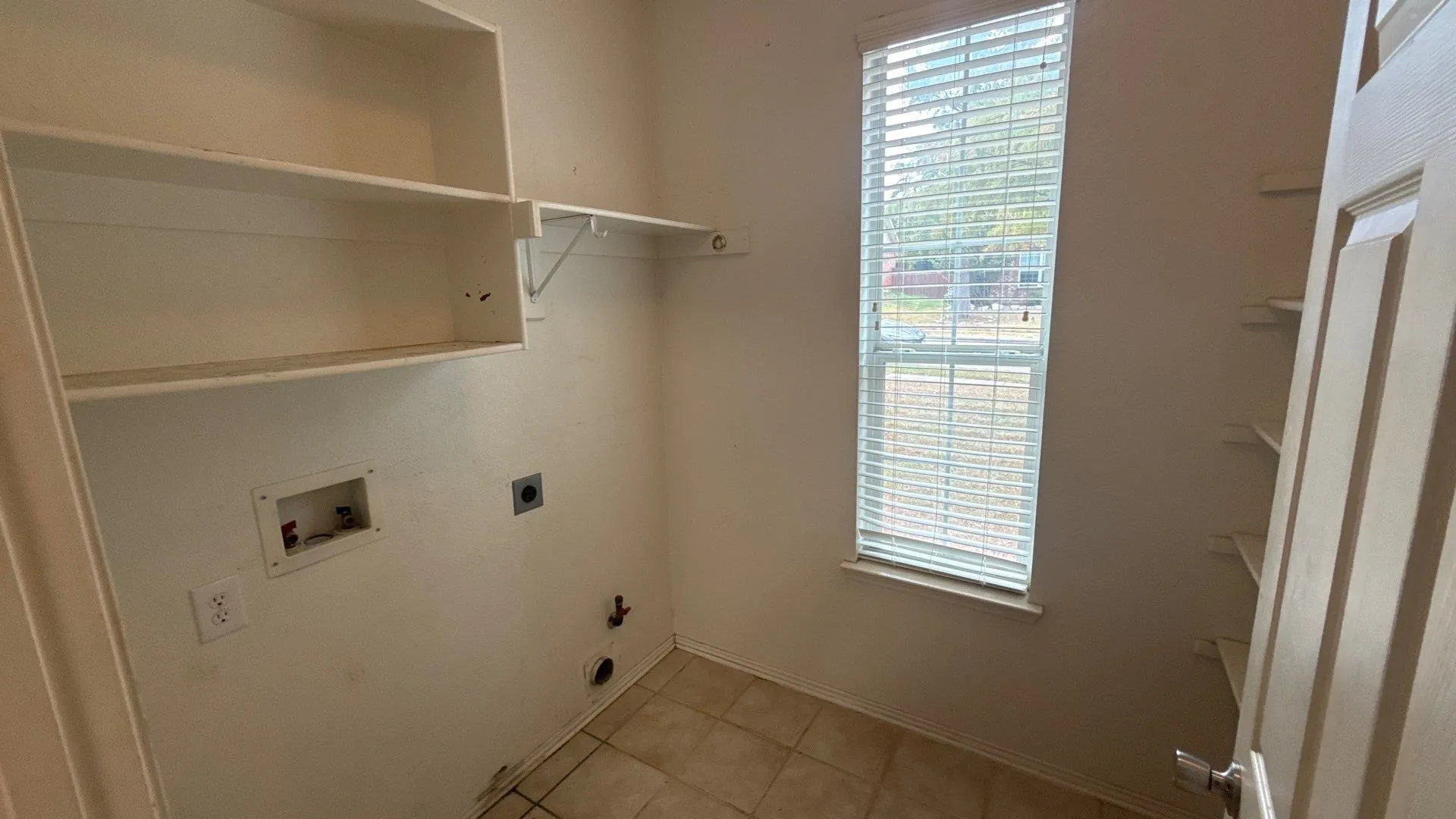 Utility room featuring built-in shelving, tile flooring, and a window with blinds