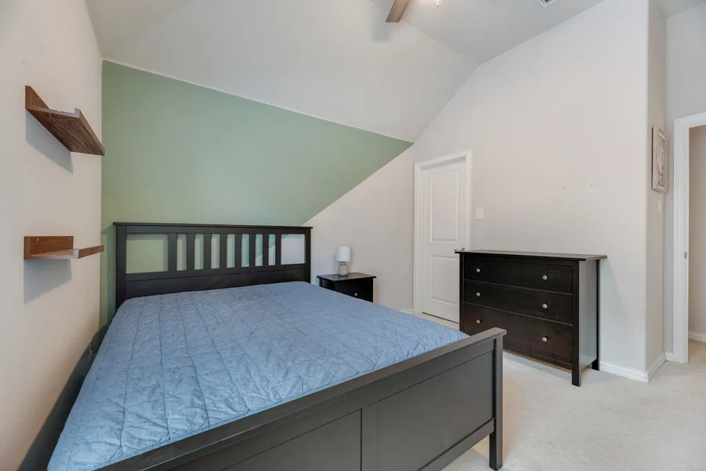 Vaulted ceiling with ceiling fan, wall-to-wall carpeting, and a built-in wall niche