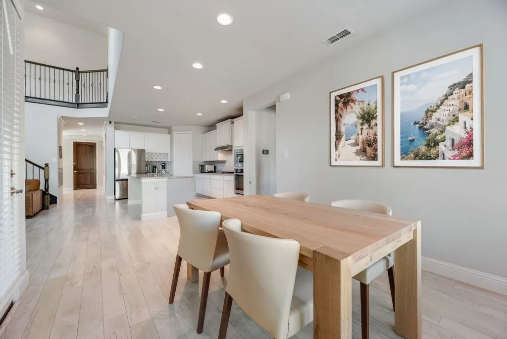 Kitchen and dining area featuring wood-finish flooring, recessed lighting, and a two-story foyer with an iron railing