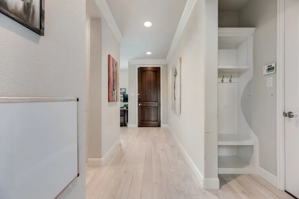 Hallway featuring wood-finish flooring, recessed lighting, crown molding, and a built-in storage bench with hooks and shelving
