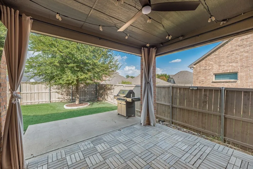 Covered patio featuring a ceiling fan, string lighting, concrete flooring, and wood-finish patio tiles
