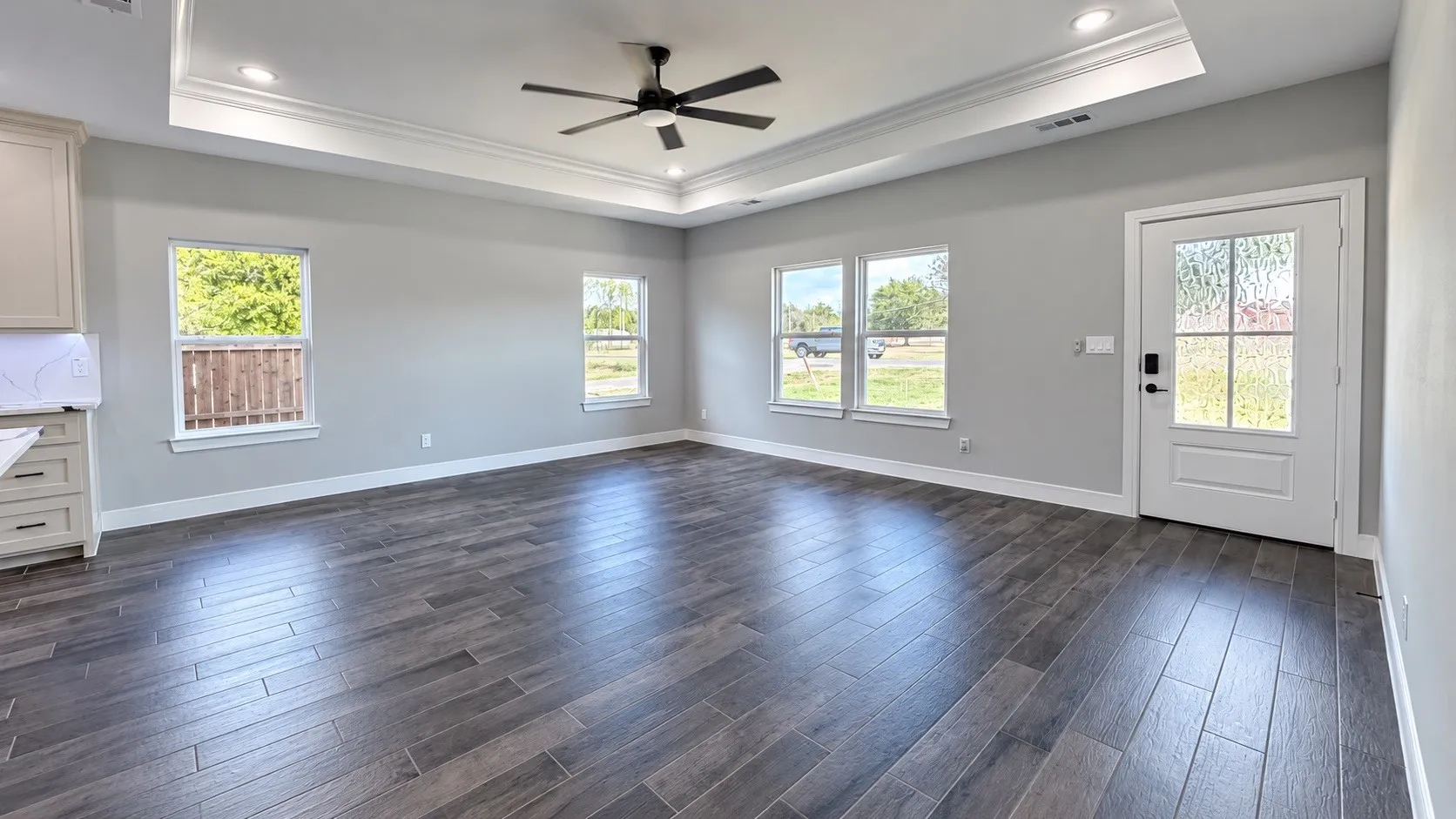 Recessed lighting, tray ceiling with crown molding, ceiling fan, wood-finish flooring, and multiple windows