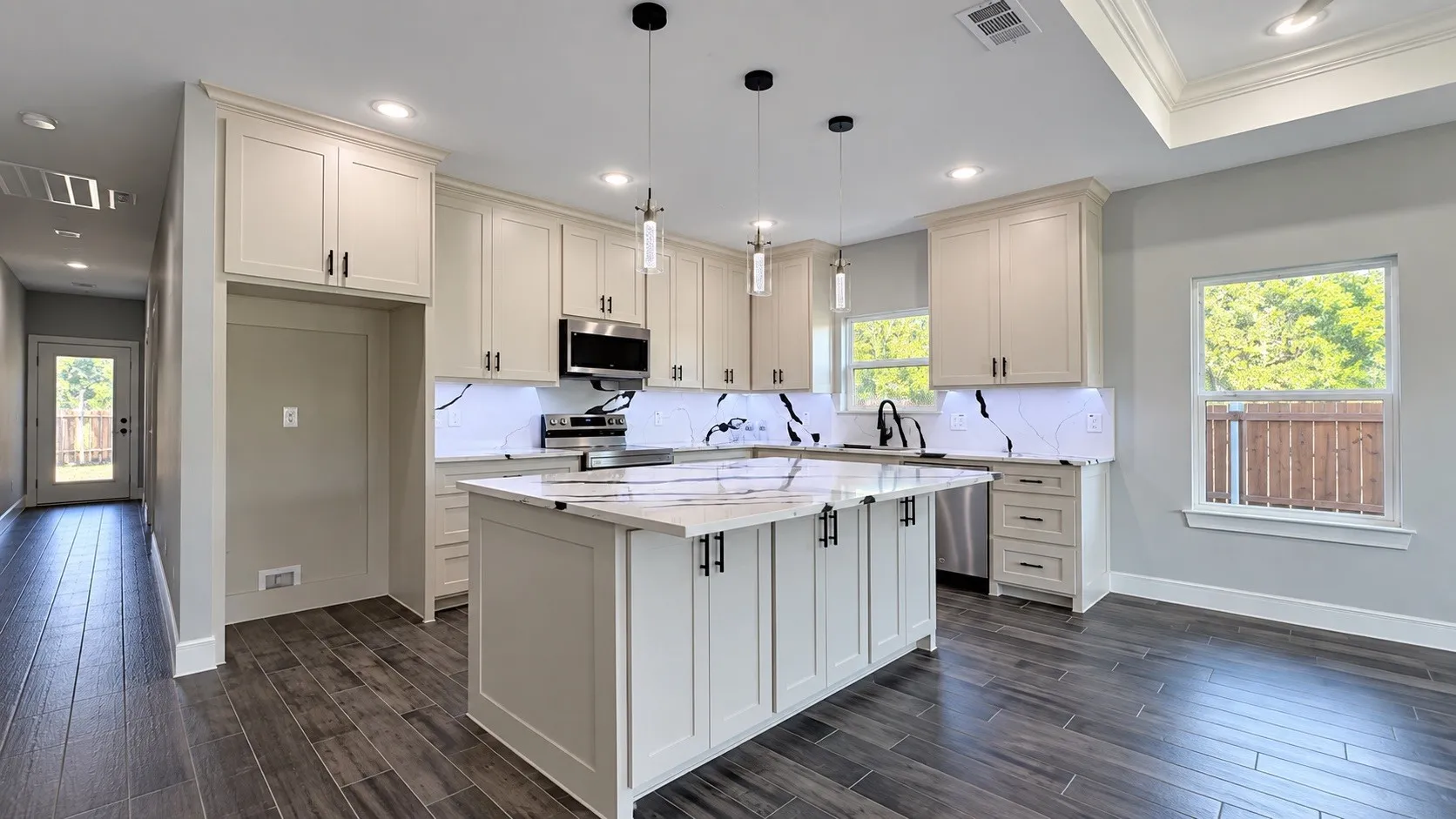 Kitchen featuring a central island, recessed lighting, pendant lighting, wood-finish flooring, and light-toned cabinetry with dark hardware